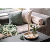 Sofakrok med puter og pledd og et lysfat med vase og lysestake på bordet