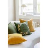 Sofa fylt med puter i gult og grønt