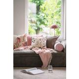 Sofa med puter og pledd i rosa toner