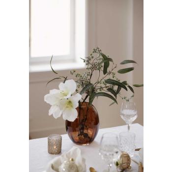 Vase med blomster og grønt på spisebord