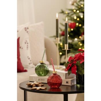 Glass julekule i rødt og grønt på sofabord med lysestake stjerne 