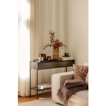 Sofa med pledd og konsollbord med vase og lyslykter