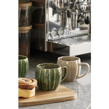 gresskar kopp på fjøl med kanelbolle