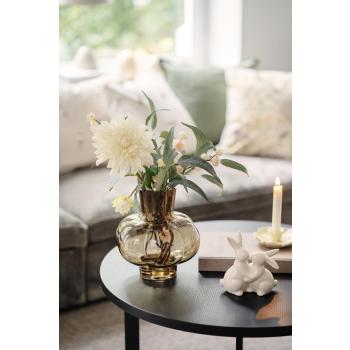 Vase med blomster og grønne blader på sofabord