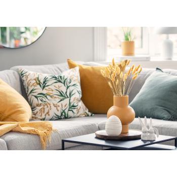 Dekoregg på bord sammen med påskeharer og gul glassvase med strå i