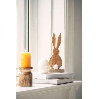 Påskeegg i vinduskarm sammen med trefigur av påskehare og kubbelysholder i tre