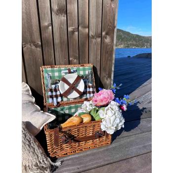 Evie piknikkurv i solvegg med blomster, puter og pledd