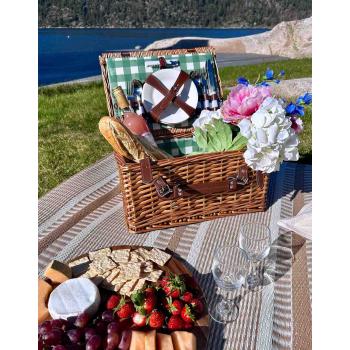 Piknikkurv på uteteppe med bær, ost og kjeks