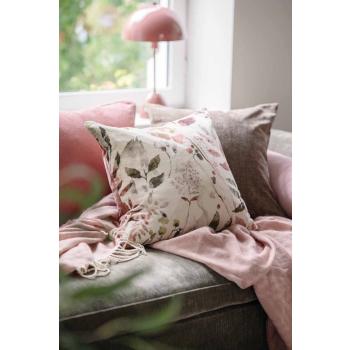 Sofakrok med puter og et pledd i rosa toner