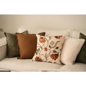 Putekombinasjon av puter i brun, grønn og hvit med en brodert pute